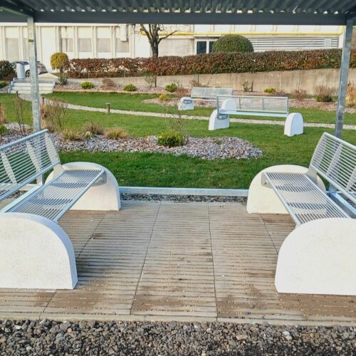 Parkbank Tauri Concrete 16 Parkbanken model Tauri Concrete met betonnen zijsteunen geplaatst in een groene parkomgeving.